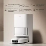 White Dreame robotic vacuum docking at a tall white base against a beige wall with feature icons above in French, highlighting tech specs.