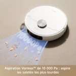 White round robotic vacuum cleaner on a beige carpet, sucking up crumbs from a blue mat. It emphasizes strong suction strength in the caption (French text unseen).