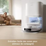 Automatic robot vacuum cleaning a living room as a woman and her dog relax on a sofa.