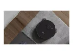 Top-down view of a circular black robotic vacuum labeled 'DEEBOT' cleaning a gray tile floor beside wood planks.