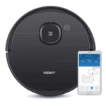 Black Deebot robotic vacuum cleaner with a connected smartphone showing the cleaning map and controls on screen.