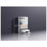Compact laboratory automation instrument with stacked modules and tubing against a dark wall, for automated sample handling.
