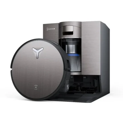 Robotic vacuum cleaner with a circular brushed-metal body next to its tall charging dock on a white background, seen from the side.