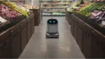 Autonomous service robot navigating down a grocery store aisle between produce sections.