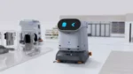 Autonomous service robot with a curved top display moving on a bright showroom floor, with clothing racks and equipment in the background.