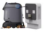 Autonomous floor-cleaning robot docked beside a wall-mounted charging station, ready for charging.