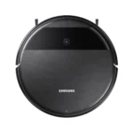 Round Samsung robotic vacuum from a top-down view with a brushed metal gray body and black band, showing its power button area and side brushes.