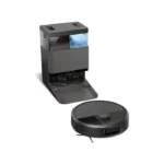 Compact gray beverage dispenser with a blue water tank beside a circular robotic vacuum on a white surface.