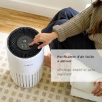 Person sits on a rug adjusting a Bosch air purifier with a digital control panel on top.