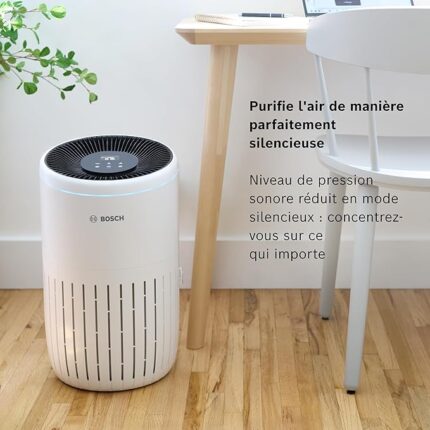 Bosch air purifier placed beside a desk and chair in a home office; quiet mode advertised in French text on image: “Purifie l'air de manière parfaitement silencieuse” and “Niveau de pression sonore réduit en mode silencieux”