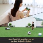 Woman indoors using a smartphone; lower half shows a sunny garden with a running child, a robotic lawn mower, a soccer ball, and potted plants; TÜV badge visible.