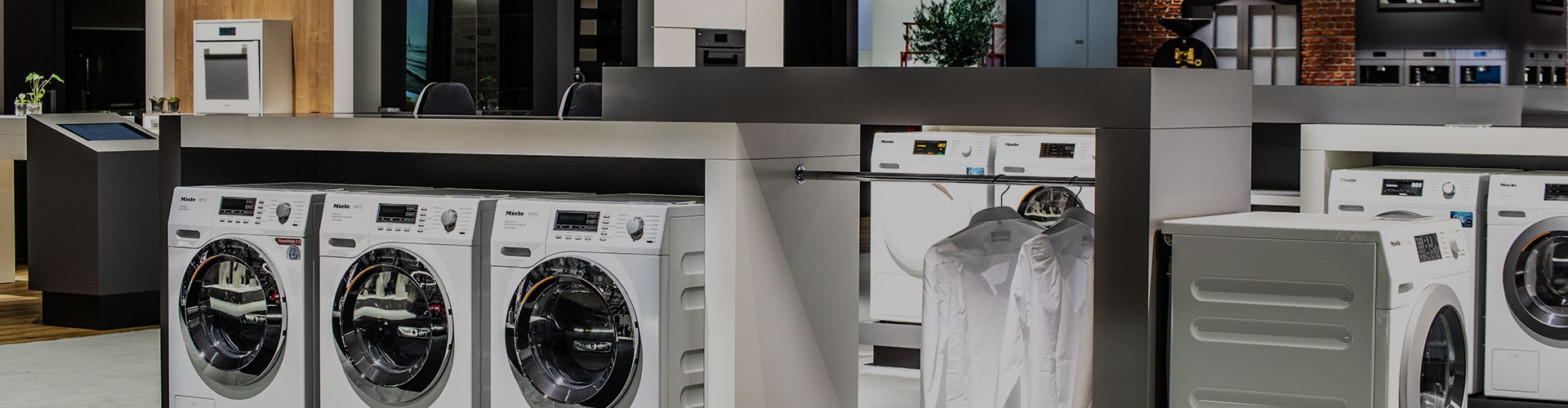 Row of front-loading washing machines on display in a modern appliance showroom