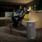 Philips air purifier in the foreground of a living room with a blurred family seated on a sofa in the background.