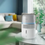 White cylindrical Philips air purifier with blue ambient light on a glass coffee table in a modern living room.