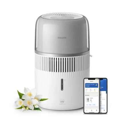 Philips air purifier with a frosted clear top and white body, shown next to a smartphone displaying its control app.