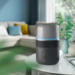 Philips air purifier with a blue LED ring, placed on a white round table in a bright living room.