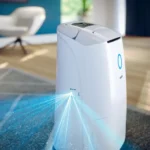 White compact home device on a living room rug projecting bright blue laser beams outward from its base.