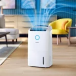 White Philips dehumidifier in a modern living room on a wooden floor, blue circular logo on the front.