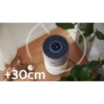 White and gray cylindrical air purifier on a wooden floor with a circular reach indicator, and a '+30cm' label in the foreground, suggesting proximity range.