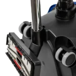 Close-up of a vacuum cleaner floor attachment with brushes and wheels, showing the chrome wand and dark housing.