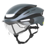 Grey Lumos cycling helmet with integrated front light and clear visor, chin straps attached.