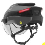 Gray Lumos bike helmet with a red rear LED light, built-in transparent visor, and a MIPS badge on the side.