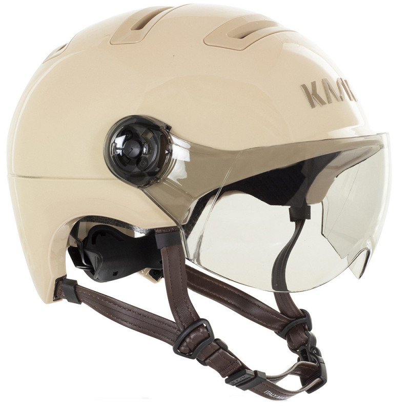 casque-de-velo-urbain-avec-visiere-kask-urban-r 12 - NEVORIXT Beige motorcycle helmet with clear face shield and brown chin straps viewed from the side/front angle.