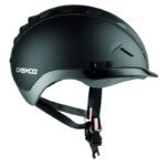 Black Casco safety helmet in side view with adjustable chin strap and quick-release buckle visible on the strap looped beneath the shell