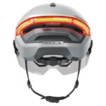 Back view of a white ABUS HYD-E cycling helmet with a bright orange rear light strip and an adjustable chin strap, emphasizing safety visibility.