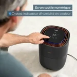 Compact air purifier/humidifier with a person touching its digital touchscreen display showing humidity and settings.