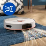 Robotic vacuum cleaner on a blue rug picking up cereal spills from a wooden floor, with motion lines suggesting suction and cleaning