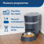 PetSafe automatic feeder beside a bowl, with blue French labels on the wall for planned meals, feed now, and slow distribution.