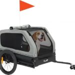 Pet bike trailer with two wheels and an orange flag, showing a happy dog inside a gray enclosure ready for a ride.