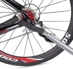 Rear bicycle wheel with red hub, derailleur cassette, and gray frame strap wrapped around the axle area