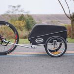 Cargo bike with a large black covered rear box and a wheel visible, parked on a road; CXWXC logo on the side.