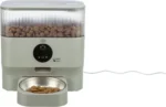 Automatic pet feeder with a transparent top hopper filled with dry kibble and a front-facing control dial over a feeding bowl below.