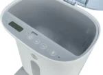 Bread machine with lid open, showing control panel with display screen and plus/minus buttons.