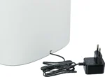 White, rounded device with a black power adapter and cord plugged into its base (side view).