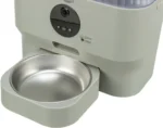 Close-up of an automatic pet feeder with a round black control panel and a removable stainless steel feeding bowl