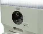 Close-up of a TRIXIE automatic pet feeder front panel, showing a black circular control area with a camera lens and a 'FEED' button.