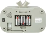 Back view of a gray electronic device with its battery compartment open, showing three AA Energizer Max batteries; power switch and speaker grille are visible on the left.