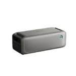 Rectangular silver portable Bluetooth speaker with a front grille and a blue power button on the right.