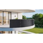 Curved modern balcony with dark privacy screens along a glass railing, overlooking a green lawn and trees.