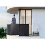 Man standing on a balcony beside a modular solar panel array mounted on the railing.