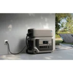 Portable power station connected to a wall outlet, charging from a nearby solar panel outside.