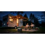 Couple sits in camping chairs outside a motorhome at dusk, with string lights overhead and a portable heater nearby.