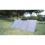 Portable solar water heater panel tilted on grass in a park with trees in the background.