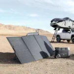 Portable solar panels set up in a desert campsite with a compact EcoFlow power station nearby, next to a vehicle with a rooftop tent.