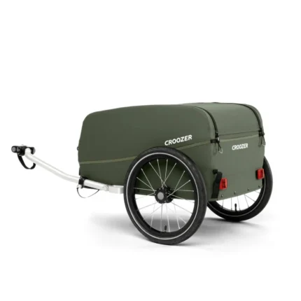 Olive-green Croozer bike trailer with two wheels and a closed cover, hitched for towing.