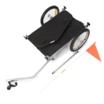 Towable bicycle trailer with a black fabric cargo bed, two large wheels, and an orange safety flag.